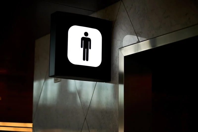 An image of a lit up black and white men's bathroom icon.